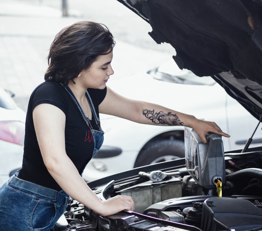 Woman adding fluids to her engine in order to keep her car from overheating