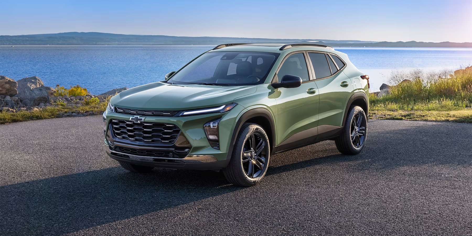 Three-quarters view to the 2024 Chevy Trax ACTIV in Cacti Green in front of the ocean