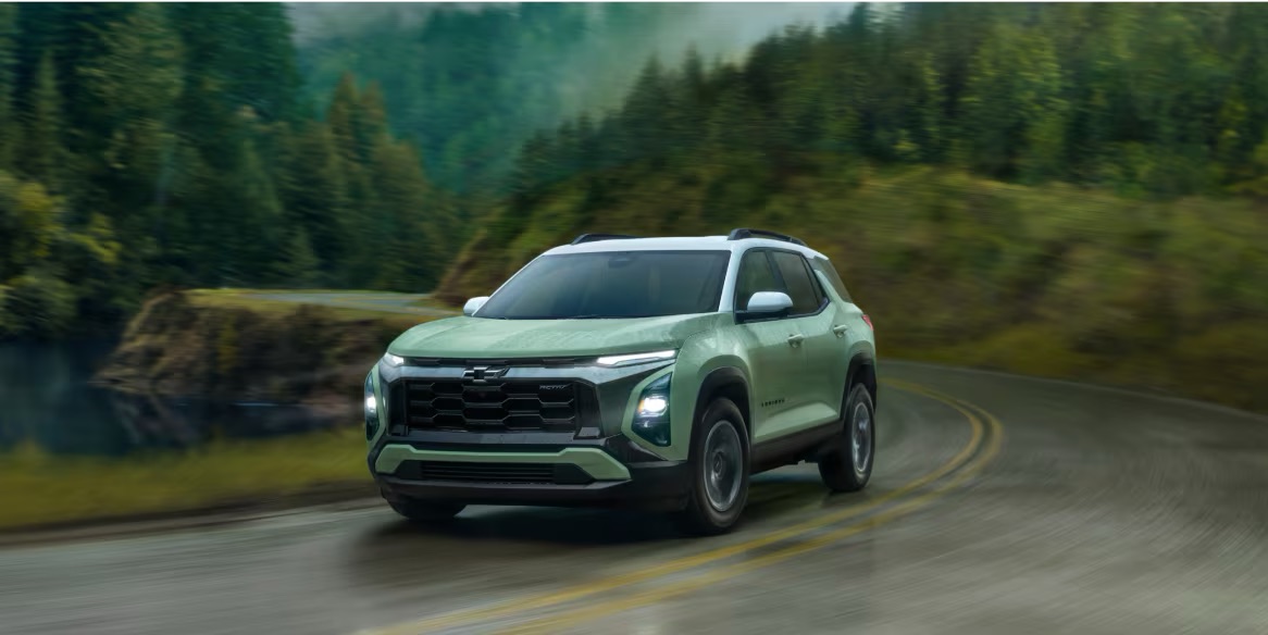 A green 2025 Chevy Equinox driving on road in rain.